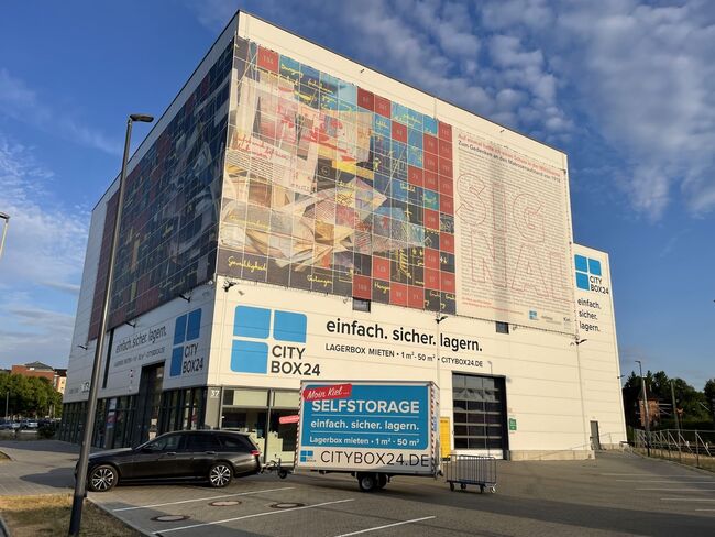 Die Außenansicht des City Box 24 Standorts in Kiel zeigt ein hohes Gebäude mit Flachdach und dem blauen Markenlogo.